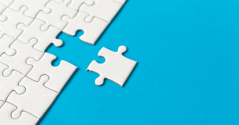 A puzzle piece sitting slightly apart from a white jigsaw puzzle on a blue background, not quite fitting into place