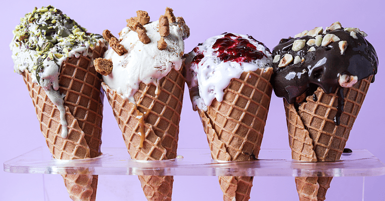 Assorted ice cream cones topped with sauces and nuts.